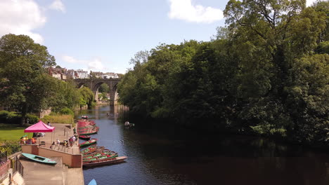 Time-Lapse-of-Rowboats-on-a-River-with-a-Victorian-Viaduct-in-the-Background