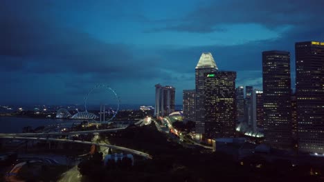 Seitliche-Luftdrohnenaufnahme-Der-Skyline-Von-Singapur-Am-Abend