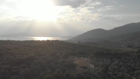 AERIAL-drone-footage-of-green-forest-at-Pelion-mountain-at-Greece-Aegean-sea-at-background-tree-top-mountain-peak-and-outdoor-music-stage-in-forest
