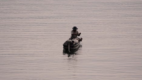 Fisherman-silhouetting-as-he-is-casting-and-drawing-his-net-in-the-River-before-dark,-in-slow-motion