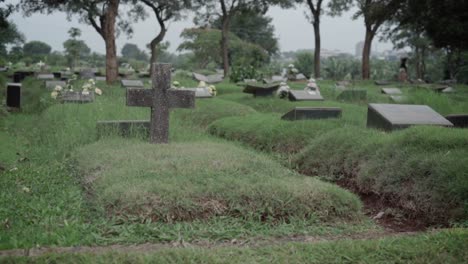 Tumbas-En-El-Cementerio-De-Césped-Con-Placas-Conmemorativas-De-Granito-Y-Cruz-De-Piedra