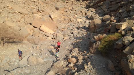 Vista-De-Pájaro-Desde-Drones-De-Turistas-Caminando-En-Montañas-Rocosas,-Emiratos-árabes-Unidos