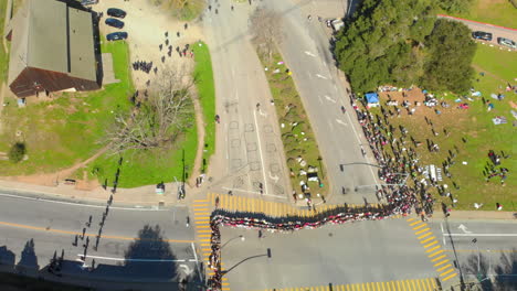 Vista-Aérea-De-Arriba-Hacia-Abajo-De-Huelguistas-De-Cola-De-La-UCSC-Uniendo-Los-Brazos-A-Través-De-La-Entrada-Principal-De-La-UCSC