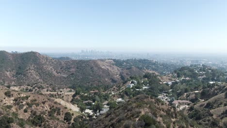 Inclinación-Aérea-Ligeramente-Creciente-Sobre-La-Colina-De-Hollywood-Con-Los-Ángeles-Apenas-Visible-En-La-Neblina-En-El-Horizonte