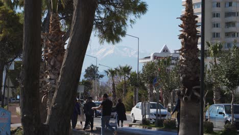 Plano-Medio,-Un-Hombre-Carga-A-Su-Hija-Al-Costado-De-La-Calle,-Gente-Caminando-En-Antalya.