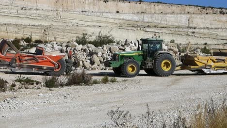 Tractor-John-Deere-Remolcando-Equipos-De-Movimiento-De-Tierra-Naranja-En-Un-Sitio-De-Construcción-Cerca-De-Torrevieja,-España