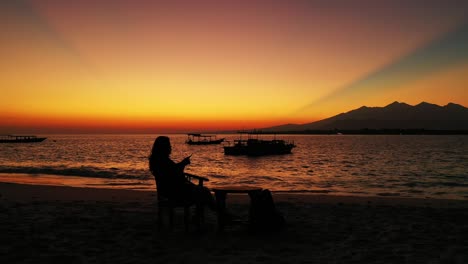 Silhouette-Eines-Mädchens,-Das-Den-Sonnenuntergang-Vom-Ruhigen-Exotischen-Strand-Der-Berühmten-Tropischen-Insel-Des-Urlaubsziels-In-Indonesien-Beobachtet