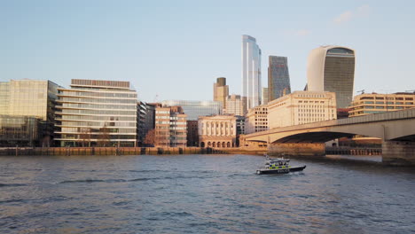 British-police-boat-over-River-Thames-with-city-skyline-of-skyscrapers