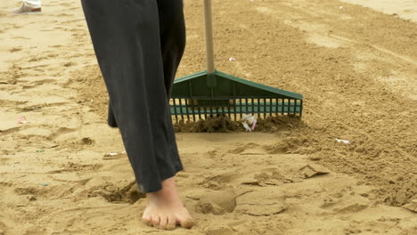 Mujer-Rastrillando-Arena-De-Playa,-Cámara-Lenta