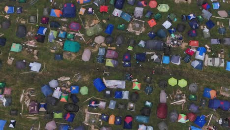 Luftaufnahme-Aus-Der-Vogelperspektive-Von-Mehrfarbigen-Zelten,-Die-Auf-Einem-Feld-Bei-Einem-Musikfestival-Aufgestellt-Wurden-Und-Auf-Denen-Menschen-Herumlaufen