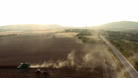 Aerial-flight-backwards-shot-of-sunflower-fields-in-Bulgarian-countryside-with-combine-harvester-and-agricultural-machinery-being-revealed