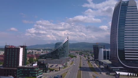 Drohne-Fliegt-Vorwärts-Und-Passiert-Moderne-Geschäftsgebäude-über-Der-Verkehrsstraße