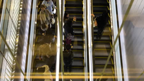 Vista-De-Arriba-Hacia-Abajo-De-Las-Personas-Que-Viajan-En-Escaleras-Mecánicas-En-La-Estación-De-Shibuya,-Japón