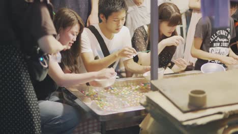 Japanese-Enjoying-Playing-At-A-Game-Booth-During-Yoiyama-Festival-At-The-Gion-Matsuri-Festival-At-Night-In-Kyoto,-Japan---Medium-Shot