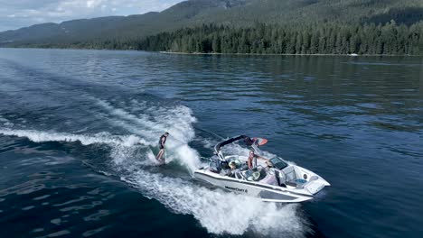 Mastercraft-Boat-Towing-Wake-Surfer-on-Glassy-Water-of-Flathead-Lake,-Montana---Aerial-Drone