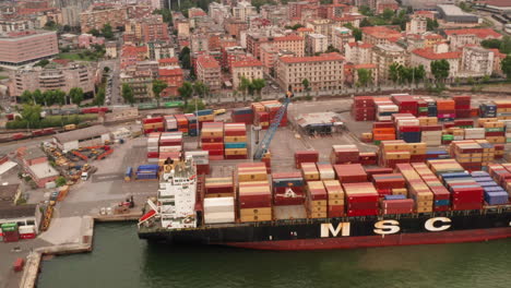 Aerial-of-stern-of-large-container-ship-docked-in-harbor