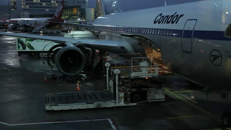 Airport-worker-checking-baggage-room-in-German-Condor-airplane