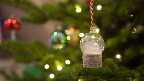 Hanging-crystal-ball-snowball-with-white-sheep-and-snow-inside-on-a-Christmas-tree