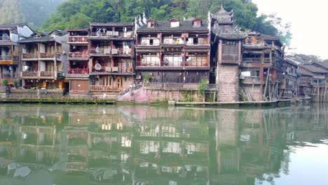View-of-the-water-reflection-of-old-historic-wooden-Diaojiao-houses-on-the-riverbanks-of-Tuo-river,-flowing-through-the-centre-of-Fenghuang-Old-Town