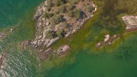 Drohne-Fliegt-Von-Einer-Kleinen-Insel-Mit-Grünem,-Durchsichtigem-Wasser-Auf-Und-Davon