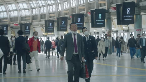 Japanese-Commuters-Wearing-Masks-Walking-Inside-Shinagawa-Train-Station-In-Tokyo---wide-shot,-slow-motion