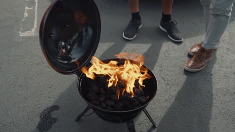 Eine-Gruppe-Von-Freunden-Zündet-Einen-Kleinen-Schwarzen-Holzkohlegrill-An