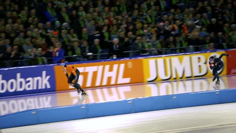 Long-wide-shot-of-two-skaters-racing-in-a-Speed-ice-skating-tournament-in-Rotterdam,-The-Netherlands