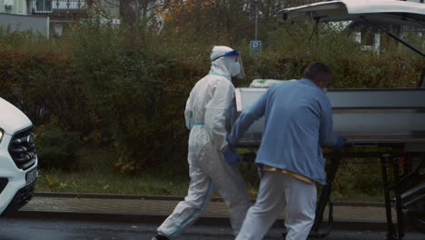 Medical-staff-in-PPE-load-isolation-chamber-on-stretcher-for-transport