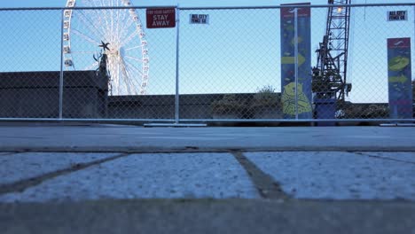 Pier-57-fenced-off-for-demolition-with-the-Great-Wheel,-ferris-wheel-in-the-background,-low-angle