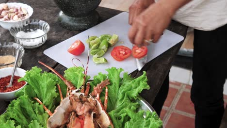 Persona-Cortando-Tomate-Con-Un-Cuchillo-Afilado-En-Una-Pizarra-Blanca-Para-Decorar-Un-Plato-De-Langosta