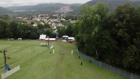 Tracking-Aerial-Shot-Of-A-Downhill-Grass-Skier-Competing-In-A-Summer-Ski-Competition-In-Europe