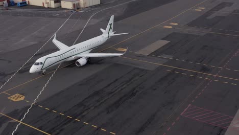 Private-jet-taxiing-on-tarmac-of-local-airport-towards-runway-to-take-off,-drone