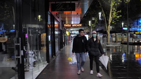 A-couple-wearing-masks-walk-down-an-Australia-street-during-the-COVID-19-outbreak