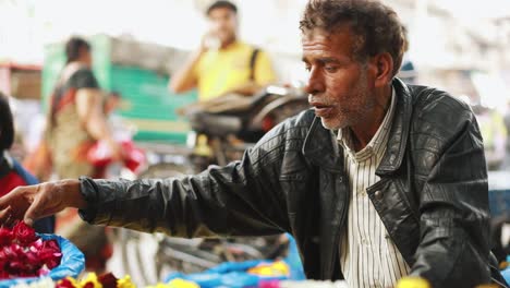 A-poor-and-old-roadside-flower-vendor-sitting-near-temple-selling-petals-and-garlands-made-of-rose-and-marigold-flowers