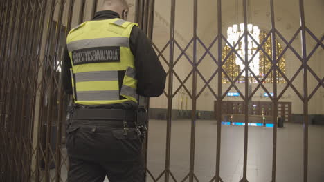 Police-man-locking-iron-lattice-door-with-metal-chain-and-padlock