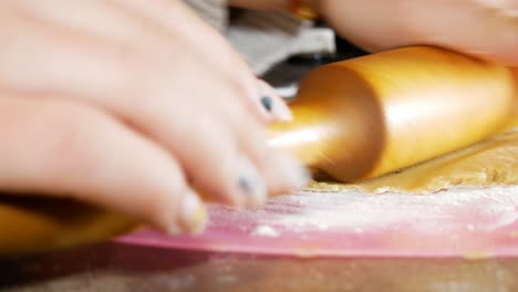 Female-hands-are-using-a-wooden-rolling-pin-for-gingerbread-cookie-dough