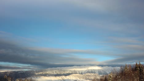 Clouds-rolling-over-the-snowy-mountain-landscape-in-winter-at-sunrise