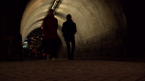 Fußgänger-Laufen-Durch-Den-Beleuchteten-Tunnel,-Während-Radfahrer-Und-Jogger-Auch-Durch-Den-Beleuchteten-Tunnel-Laufen