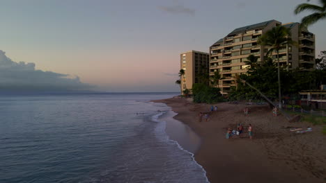 People-relaxing-on-Kahana-Beach,-Maui-at-sunset
