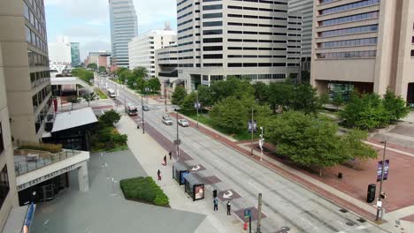 Descending-aerial-of-East-Pratt-Street-in-Baltimore-MD,USA-during-summer-day,-pedestrians-and-people-waiting-for-bus-at-public-transit-stop