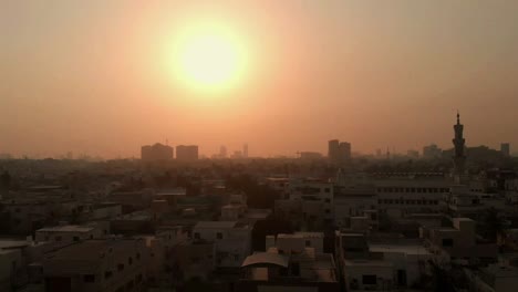 Aerial-Over-Of-Karachi-Skyline-With-Mosque-Minaret-Against-Golden-Orange-Sunset