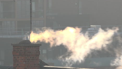 Uk-Octubre-2018--La-Luz-Del-Sol-Temprano-En-La-Mañana-Atrapa-El-Vapor-Que-Sale-De-Una-Chimenea-En-Una-Azotea-De-La-Vieja-Escuela-Frente-A-Apartamentos-De-Lujo-Recién-Construidos-En-El-Este-De-Londres