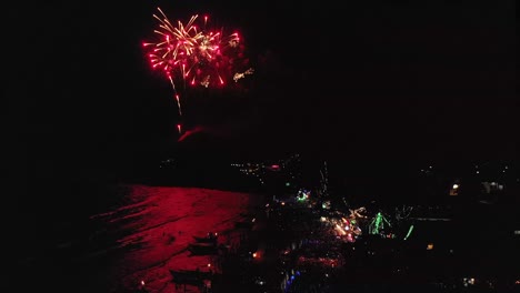 Aerial-above-dance-festival-on-tropical-island-beach-with-colorful-Fireworks