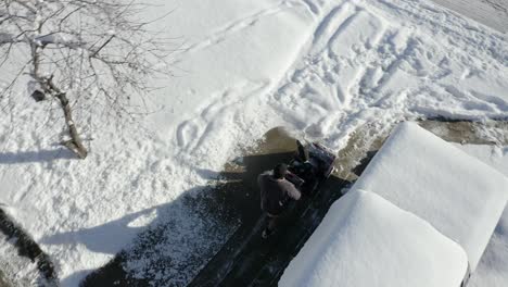 Aerial-top-view-of-man-using-snow-blower-with-camera-rotation