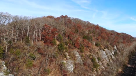 Aerial-wide-angel-of-hikers-along-cliffside-with-railroad-tracks-down-below-in-autumn-season
