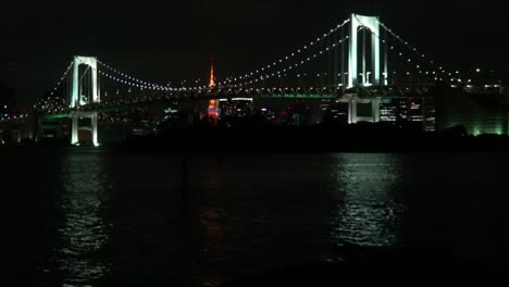 Der-Blick-Auf-Die-Regenbogenbrücke,-Den-Tokyo-Tower-Und-Die-Spiegelung-Auf-Dem-Meer-Bei-Nacht