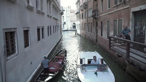 A-Gondola---a-speed-boat-pass-each-other-in-the-small-canals-in-Venice,-Italy