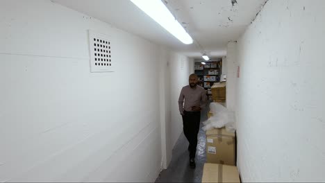 Asian-Indian-Male-walking-towards-camera-through-a-corridor-in-an-office-basement