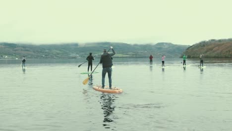 Eine-Menge-Paddle-Boarder-Stehen-Auf-Und-Paddeln-Auf-Dem-See-In-Der-Natur