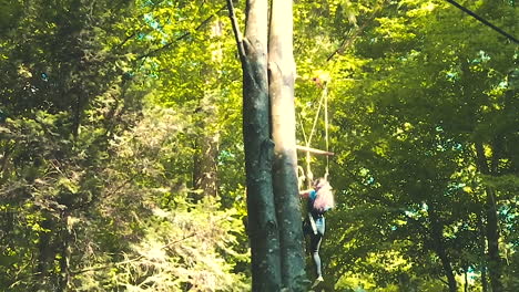 Woman-travelling-downwards-through-the-forest,-enjoying-a-thrill-ride-with-zip-wires-in-Signal-De-Bougy-Parc-Adventure,-slow-motion-footage